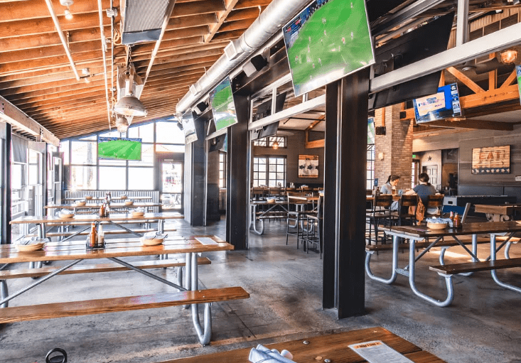 Indoor dining area at Draft Republic San Marcos with picnic-style seating and multiple TV screens.