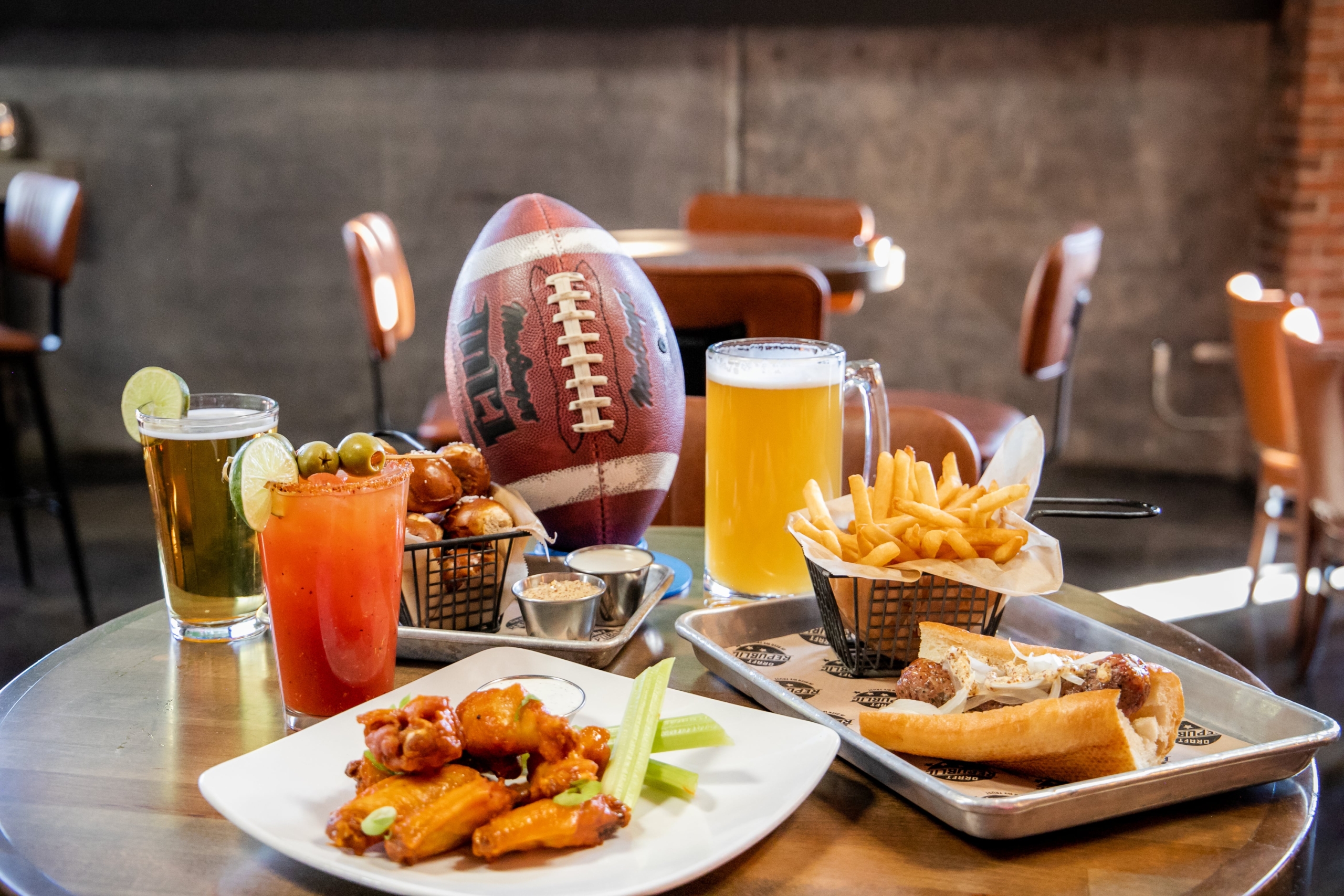 A game-day spread with wings, fries, beer, and cocktails, set for a lively happy hour in San Marcos.
